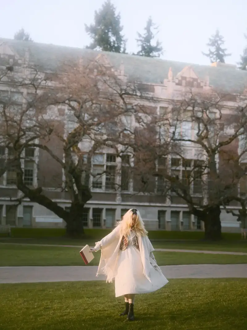 Dreamy motion-blur portrait of a girl spinning in white dress in front of UW gothic architecture at the Quad
